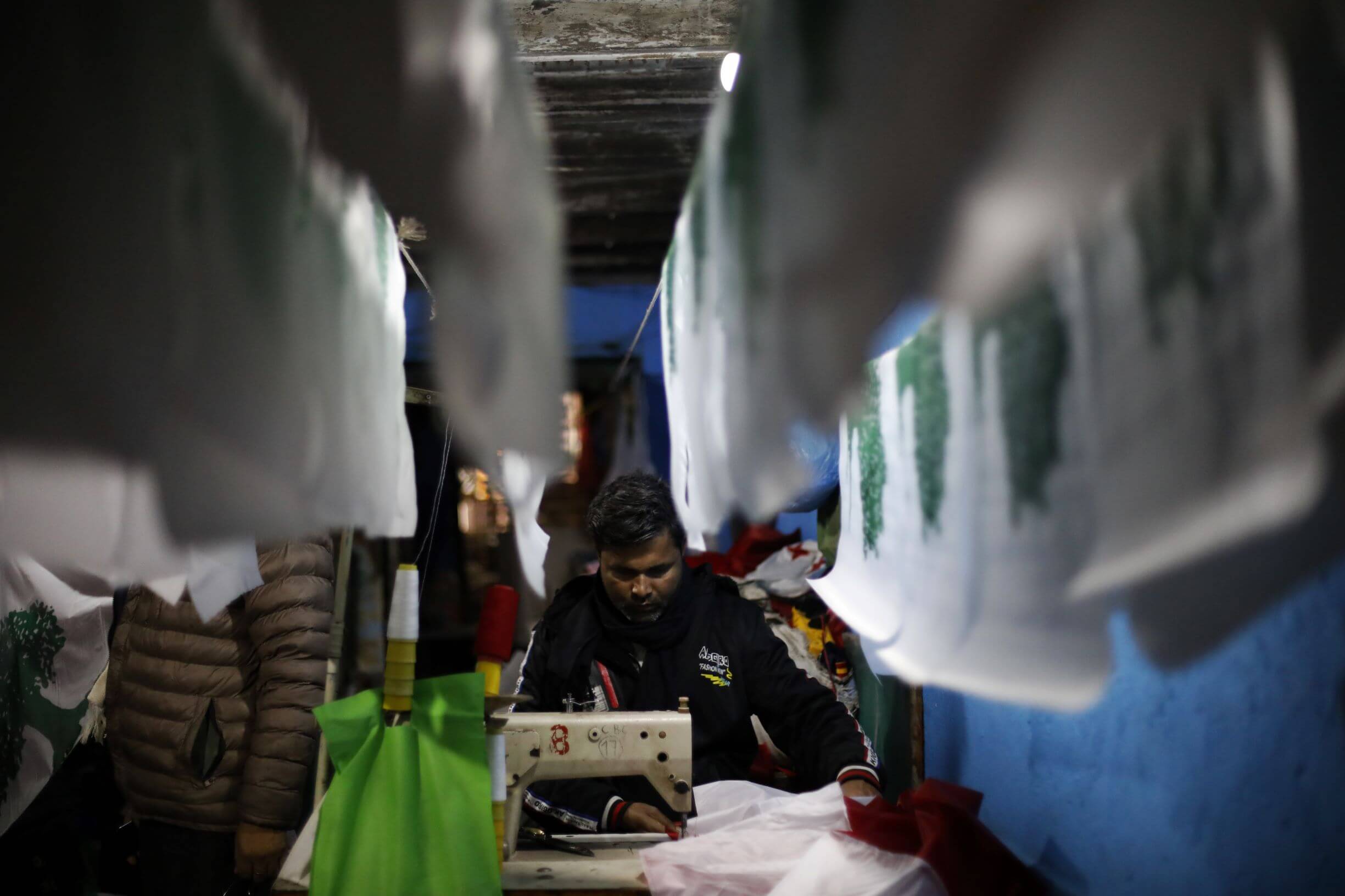 A man sewing flags in a factory in Nepal.