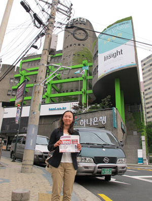 Journalism student Seulki Lee, who spent five months as a volunteer teacher in Lamjung in 2005, poses with a copy of Nepali Times outside the fortress-like office of Hyankoreh Shinmun in Seoul. 