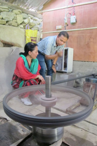 Barsha Shrestha of Clean Energy Bank inspecting an improved water mill