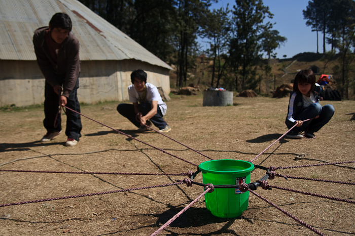 In ‘Toxic Waste’, a group attempts to carry a bucket filled with water out of a restricted area without spilling any of it or directly using their hands. An elastic ring connected to ropes is what they have to use. 