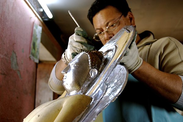 Swayambhu renovation 2010, Kathmandu, Nepal Artist Lok Ratna Shakya applying a gold-mercury mix to the a statue from a Toran of Swayambhu.