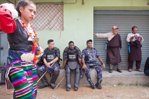 A Tibetan woman walks past a group of policemen at the Jawlakhel refugee camp, during the celebration of Dalai Lama's 79th birthday. (Photo: Basi Edward Teo)