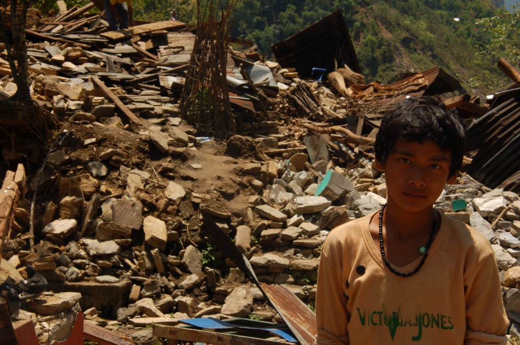 A boy stands infront of the rubble of his house where six people were buried. 